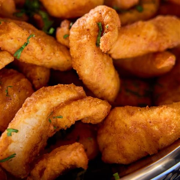 Close-up of golden-brown fried Indian pakoras or fritters, sprinkled with green herbs.