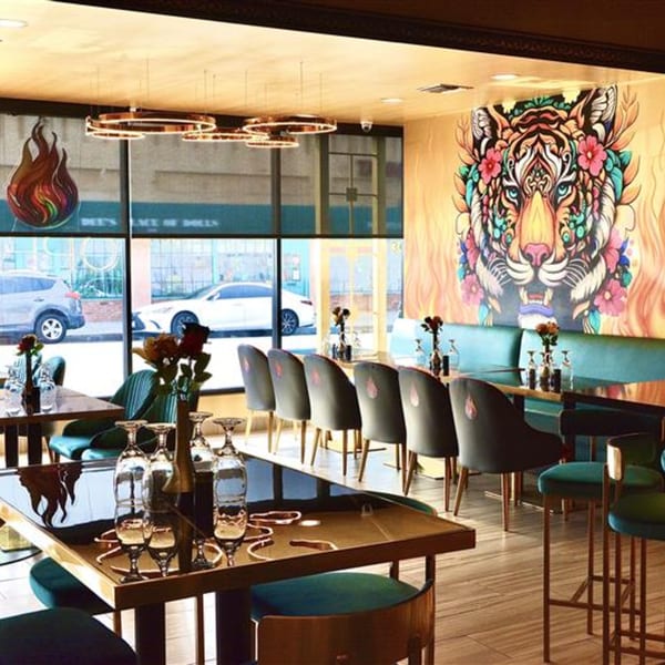 Agnii restaurant interior with a colorful tiger mural, modern lighting, and teal seating.