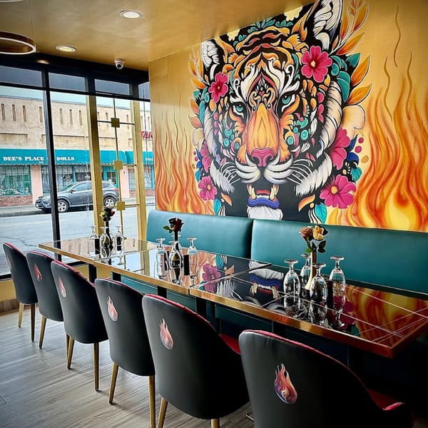 Agnii restaurant interior with a vibrant tiger mural, long dining tables, and teal booth seating.