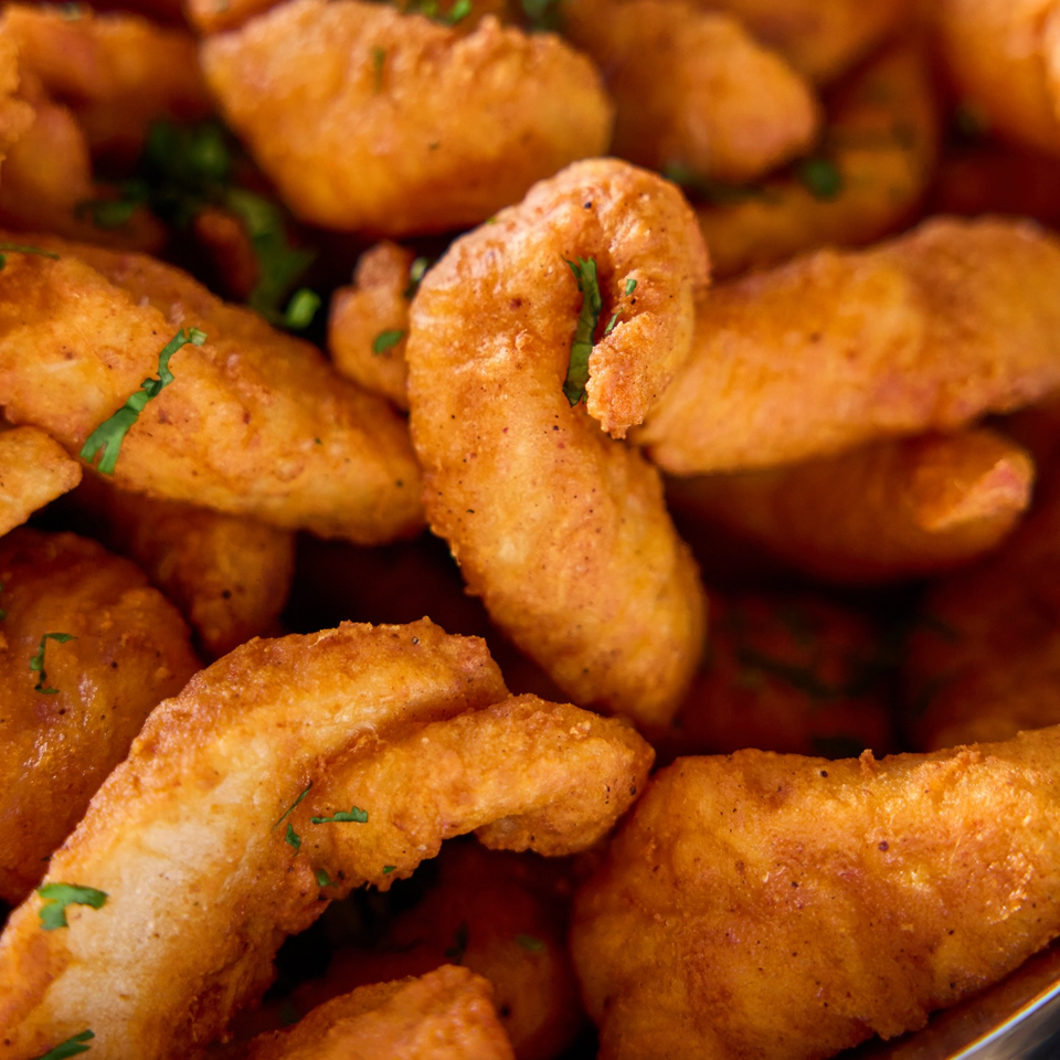 Close-up of golden-brown fried appetizers garnished with chopped herbs.