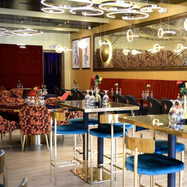 Agnii restaurant interior with modern lighting, red and gold decor, and blue velvet bar stools.