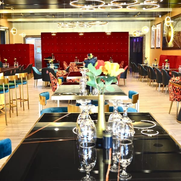 Elegant Indian restaurant interior with red velvet walls, black tables, and gold accents.