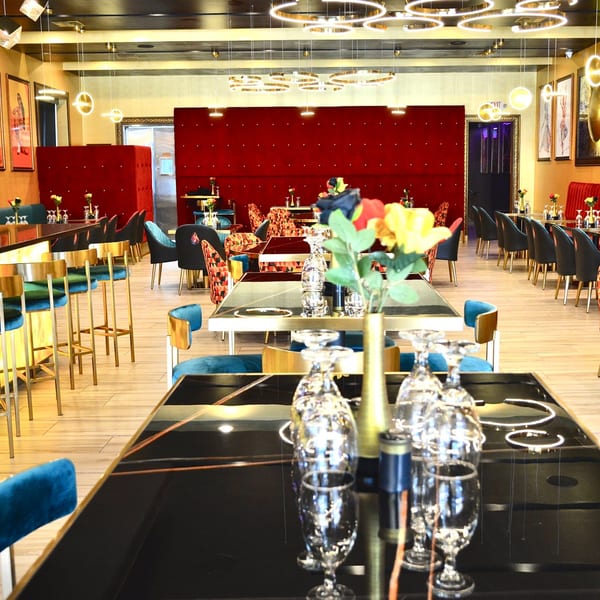 Agnii restaurant interior with red velvet walls, black tables, and blue and gold chairs.