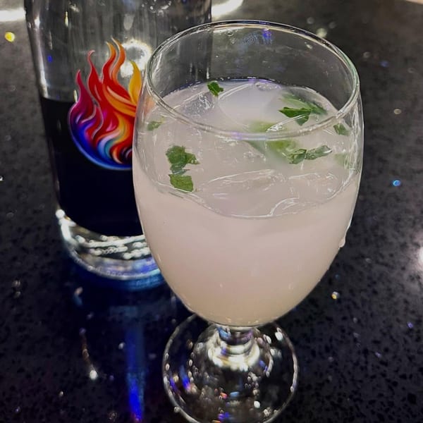 A refreshing Indian drink with mint and ice, next to a glass bottle with a fiery logo.